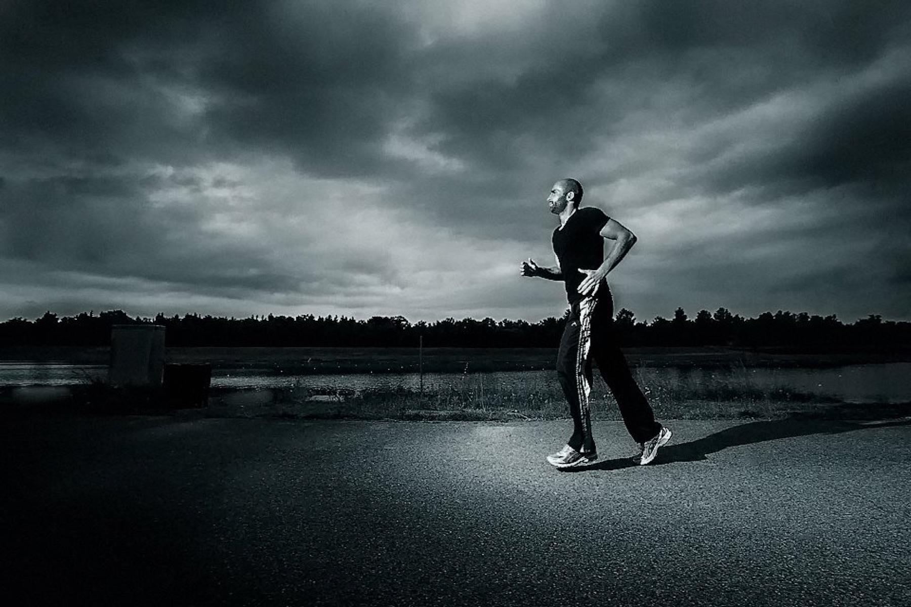 Telat beim Lauftraining unter dramatischem Himmel, schwarz-weiß